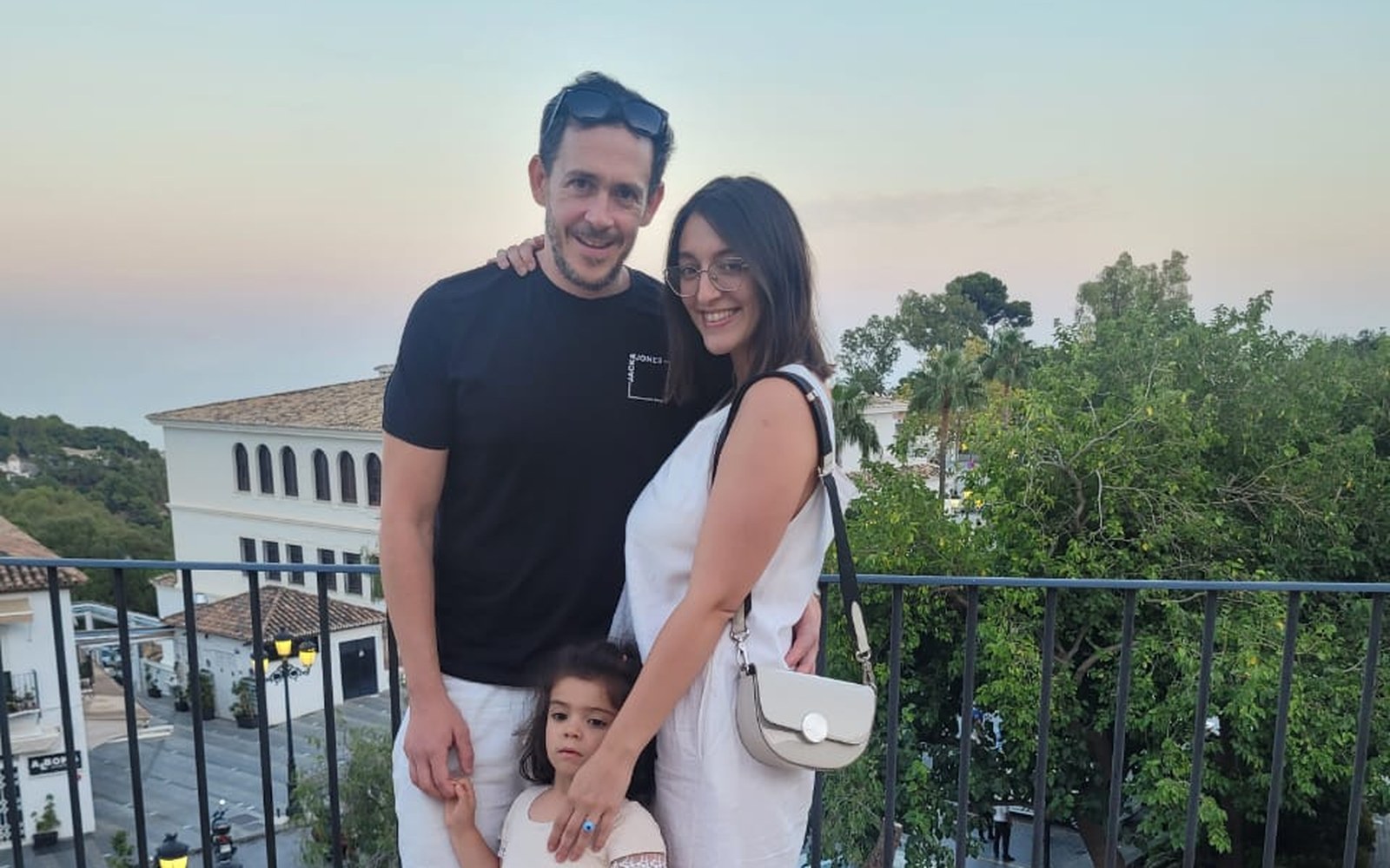 Elena Ghita with her husband and their six-year-old daughter on a terrace overlooking a Costa del Sol village at sunset